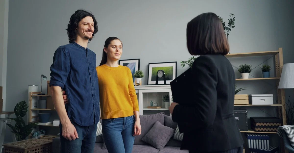 Un couple souriant rencontre un agent immobilier dans un salon élégant.