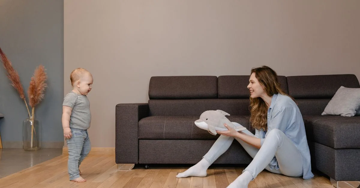 Un moment joyeux entre une mère et son bébé jouant sur le sol du salon avec un jouet dauphin.