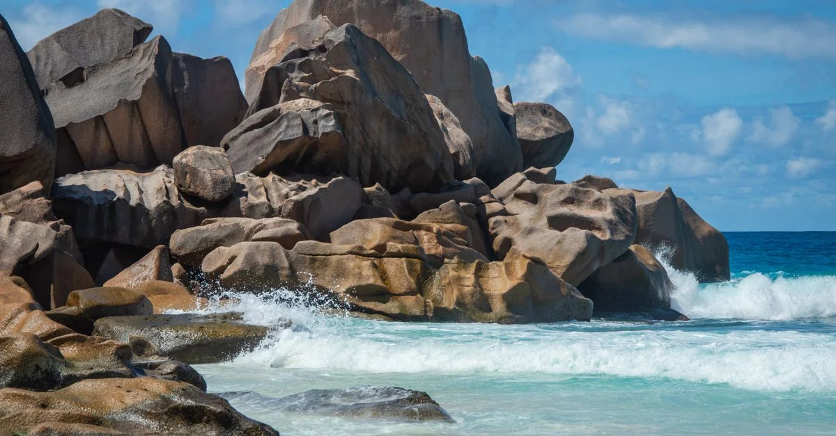 Rochers de granit et vagues turquoise sur une plage ensoleillée, évasion nature.