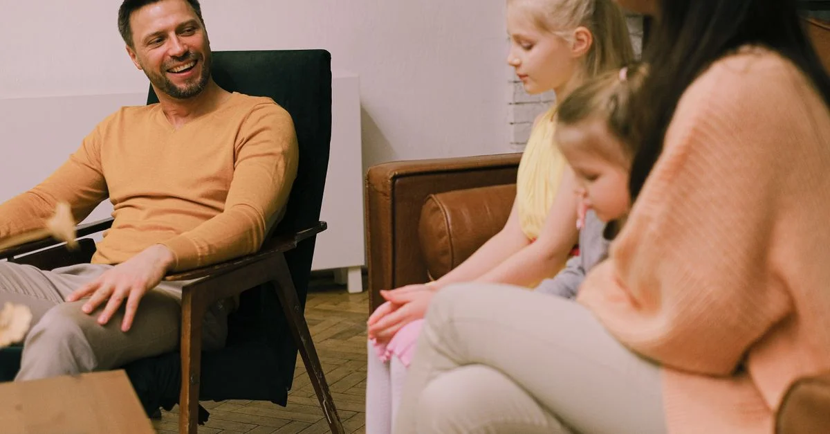 Une famille joyeuse assise ensemble dans le salon, échangeant des sourires et des conversations.