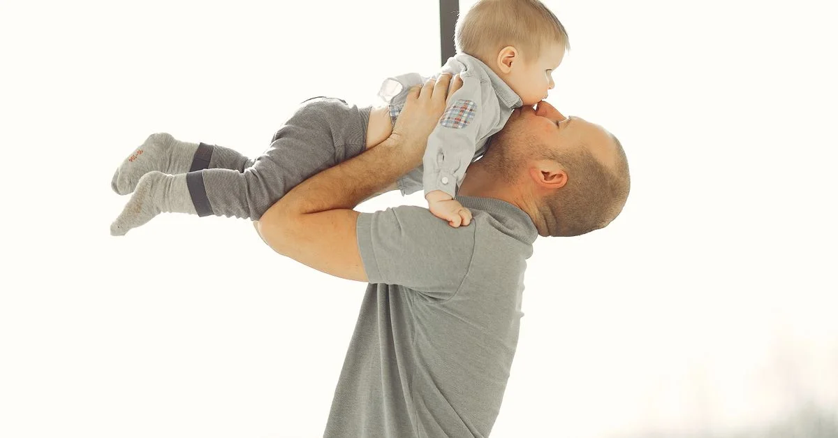 Un père soulève tendrement son bébé, montrant un lien affectueux entre parent et enfant.