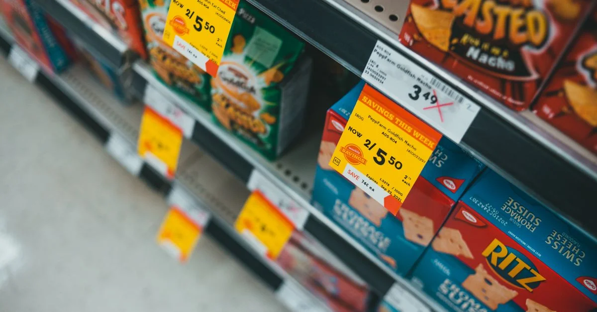 Rayon de supermarché présentant des collations en promotion avec des étiquettes de vente et des prix visibles.