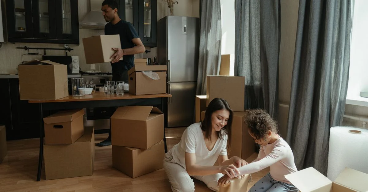 Une famille déballe des cartons dans la cuisine de son nouvel appartement, symbolisant un nouveau départ.