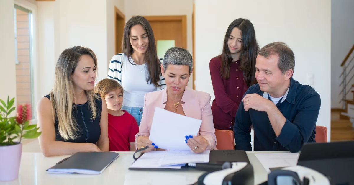 Une réunion de famille avec une agente immobilière examinant des documents dans une pièce moderne et lumineuse.
