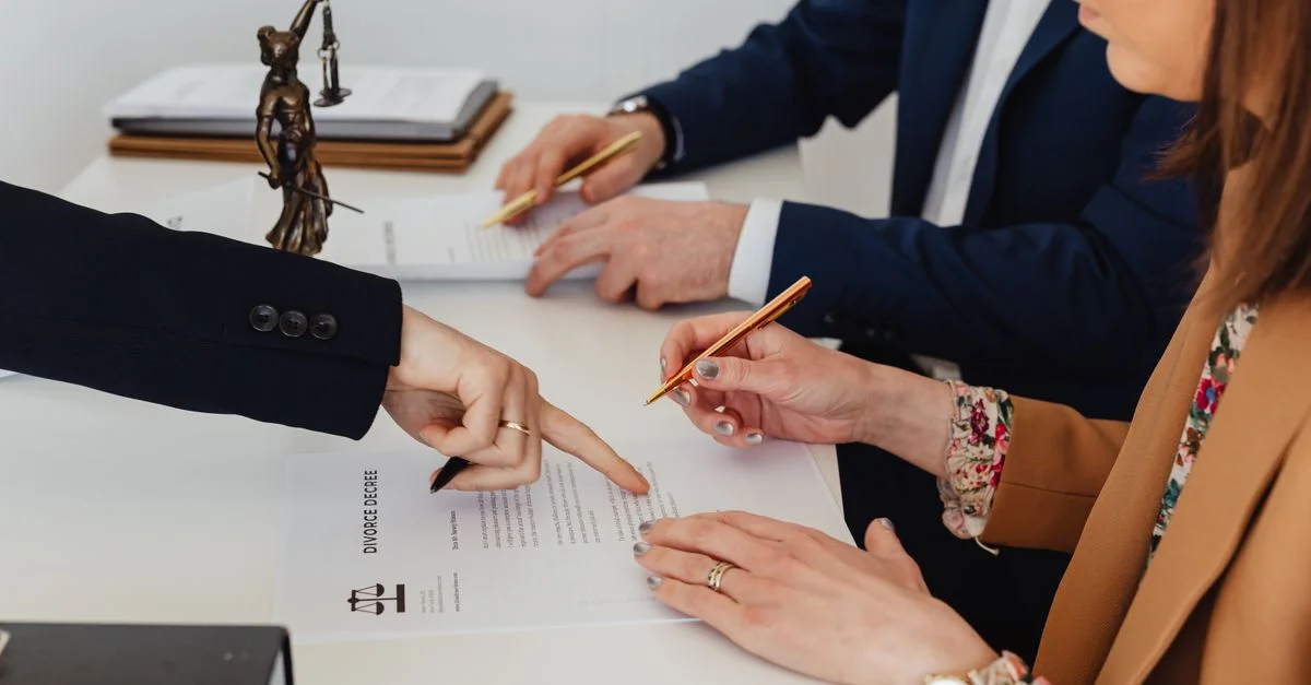 Mains signant un décret de divorce, avec une statue de la justice à proximité, symbolisant les procédures légales.