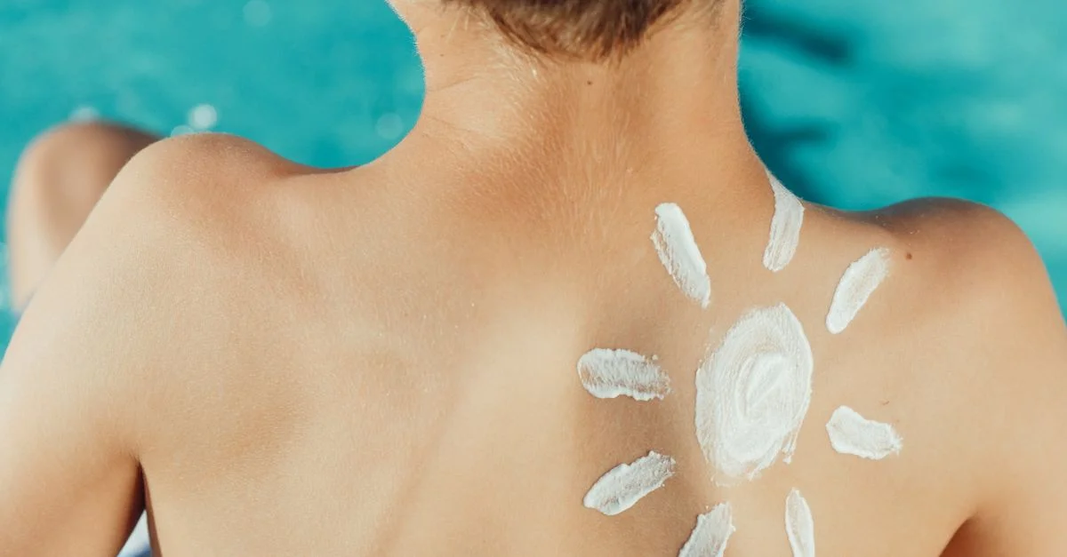 Le dos d'un enfant avec de la crème solaire en forme de soleil, profitant d'une journée ensoleillée près de la piscine.
