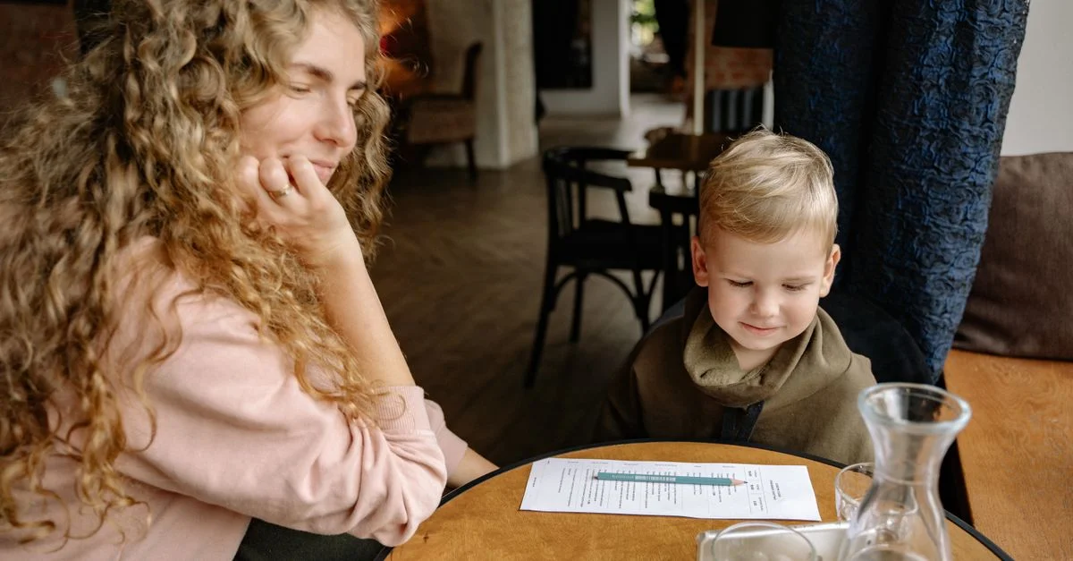 Une femme et un jeune garçon partagent un moment confortable à une table de café, à l'intérieur.