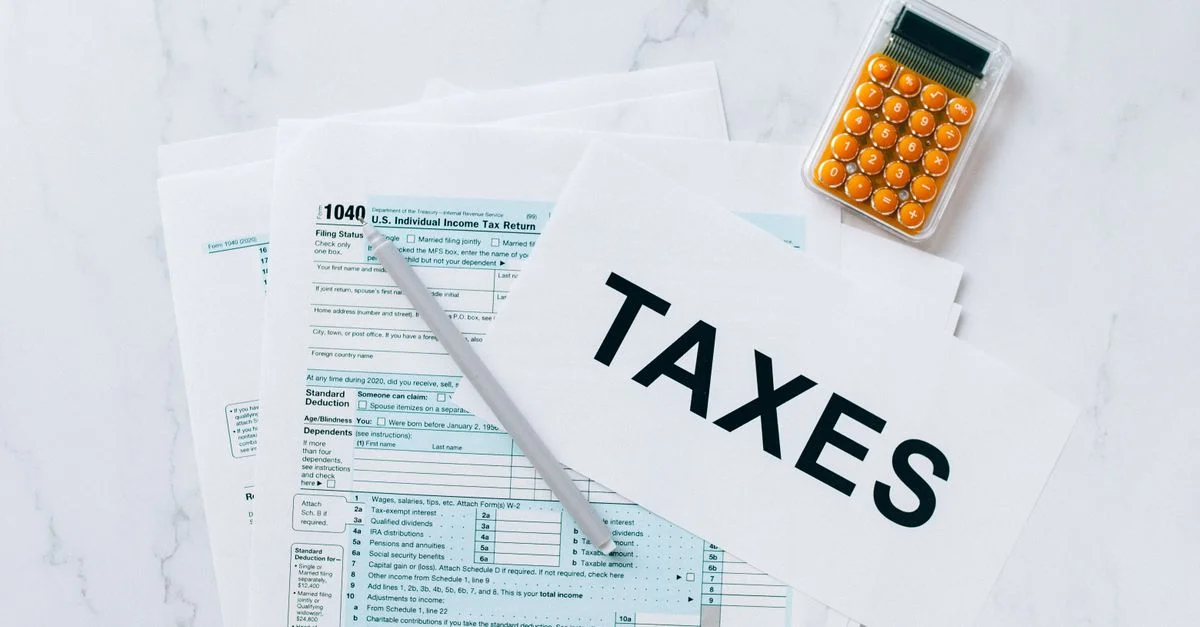 Vue de dessus des formulaires fiscaux, d'une calculatrice et d'un stylo pour la préparation des impôts.