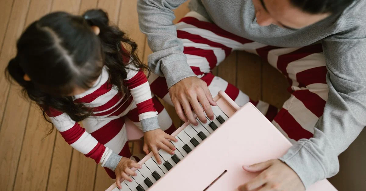 Un moment réconfortant entre un père et sa fille jouant sur un piano jouet rose à la maison.