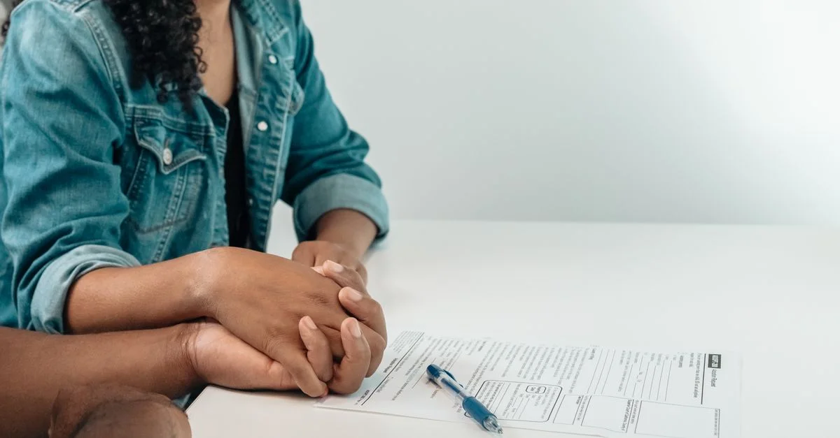 Un couple se tient la main sur des papiers d'adoption, symbolisant l'unité familiale et le soutien dans un cadre légal.